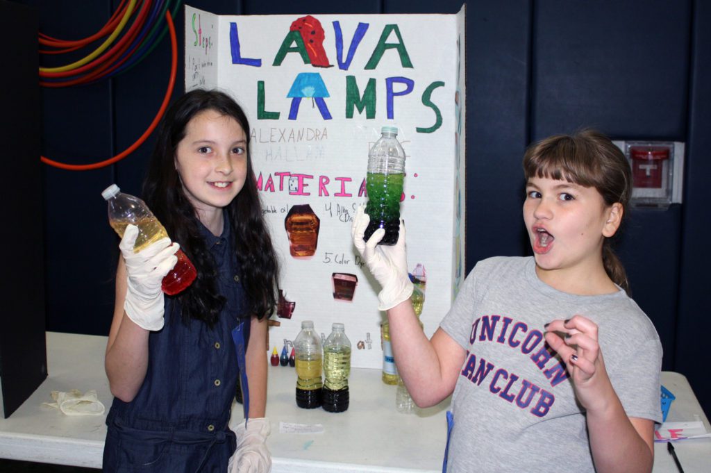 students hold up lava lamps they made