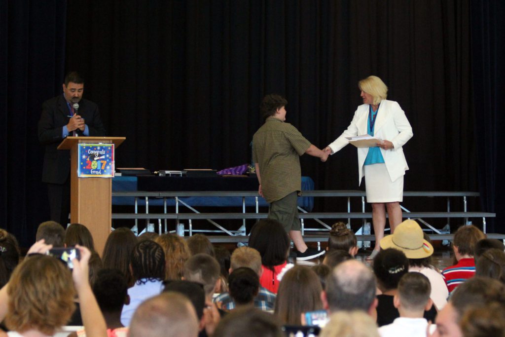student walks across stage to shake hands with Mrs. Schlenker