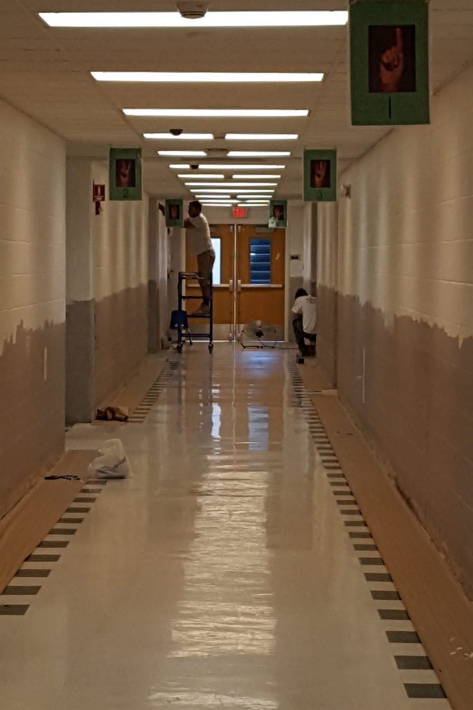 two painters painting beige hallway