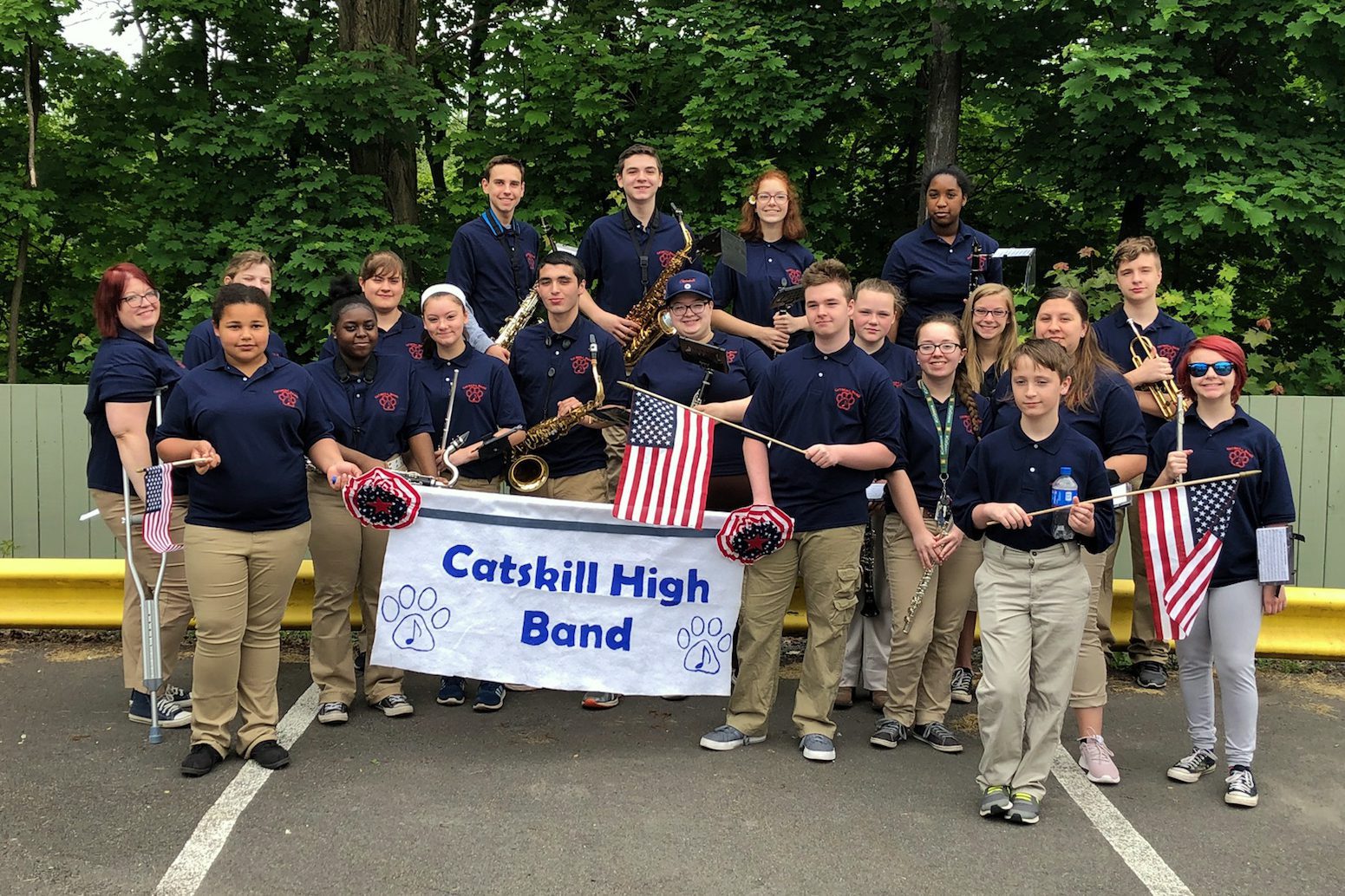 High school band and a few middle school band members pose with band banner