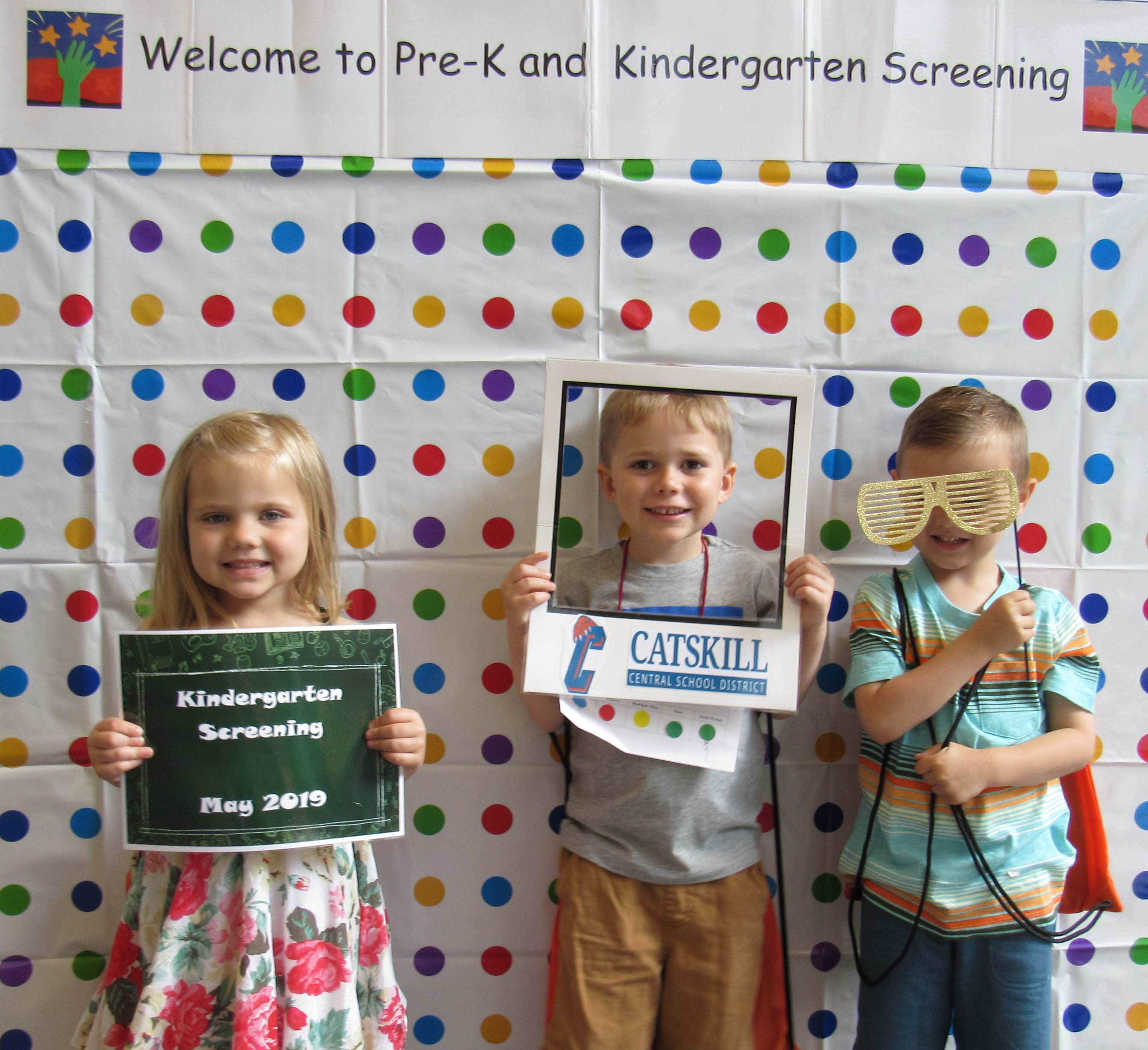 one girl and two boys pose with sign, frame, and silly glasses