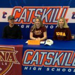 Katie Bulich sitting at table wearing Iona Soccer t-shirt and flanked by man and woman whee Iona College clothing