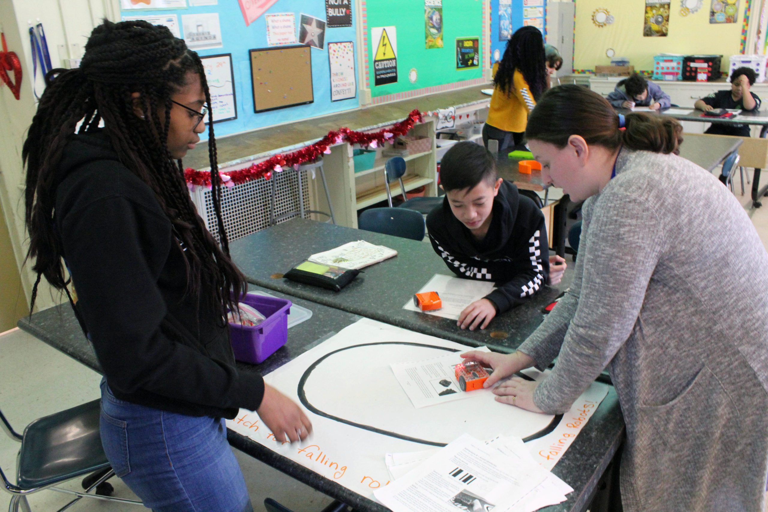 gril, boy, and woman palcing robot in ring on table