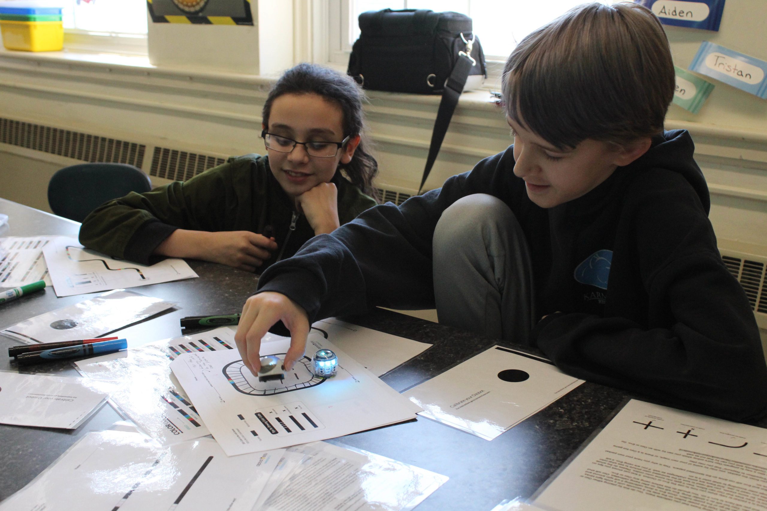 two boys palying with tiny dome shaped robot