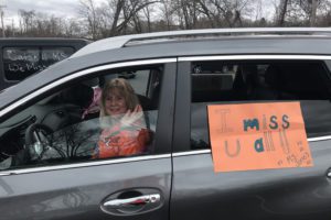 dog and woman in car with sign that says Miss U Guys