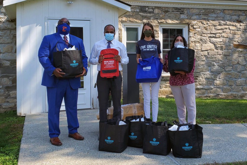 Two men and two women posing with bags of PPE