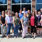 New faculty pose for photo outside CHS