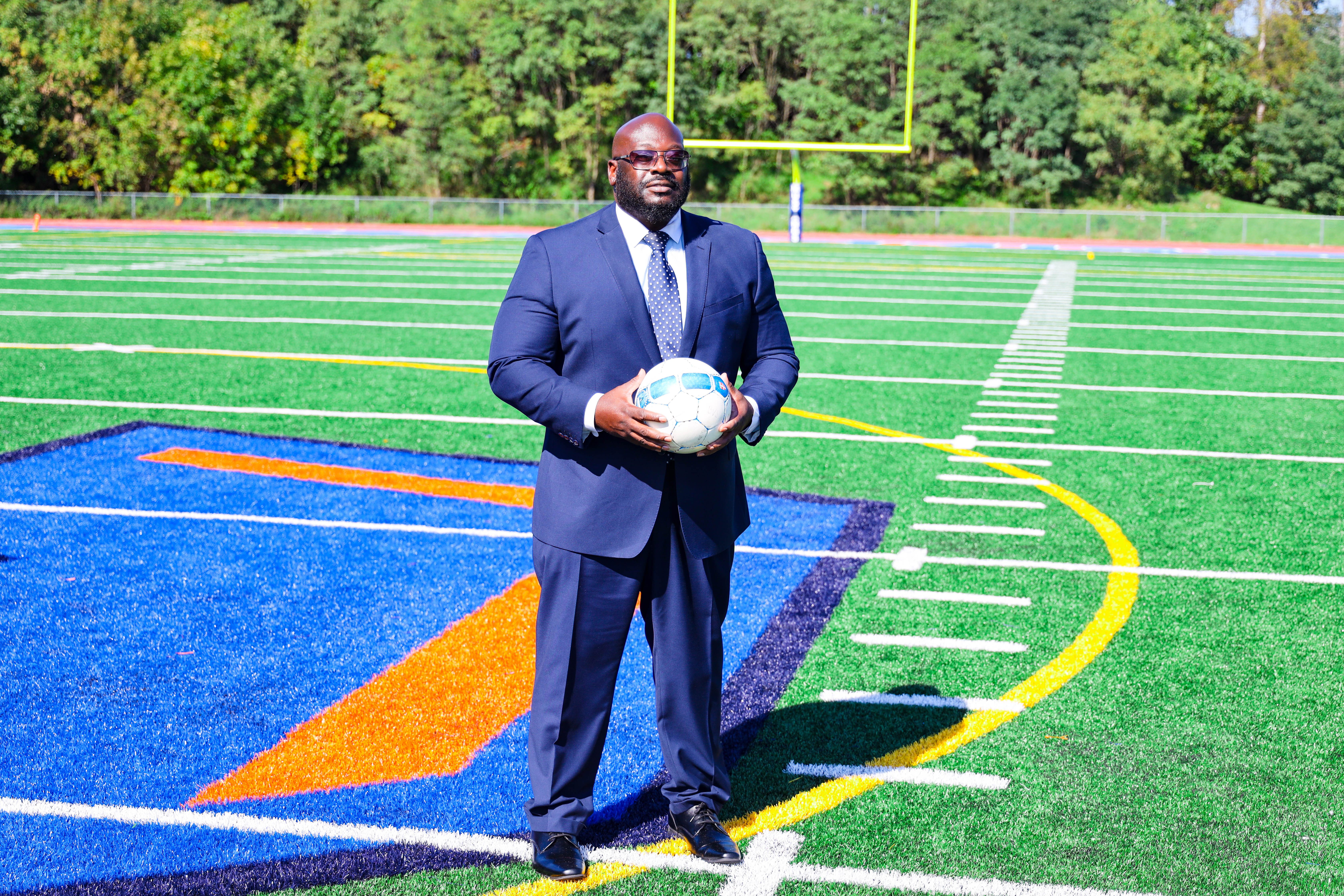 Dr. Cook holding soccer ball on turf field