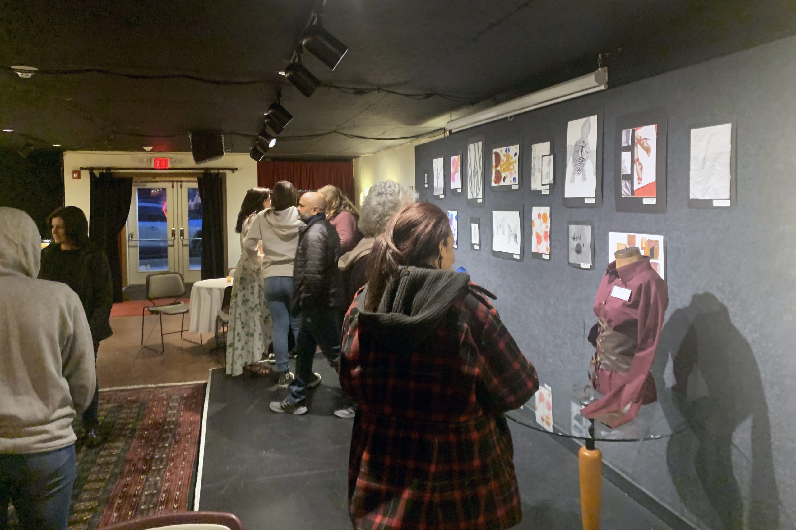 crowd checks out student drawings, sculpture, and fashion on display