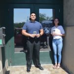 police officer and teenage girl pose next to Catskill Police Patch on police department door