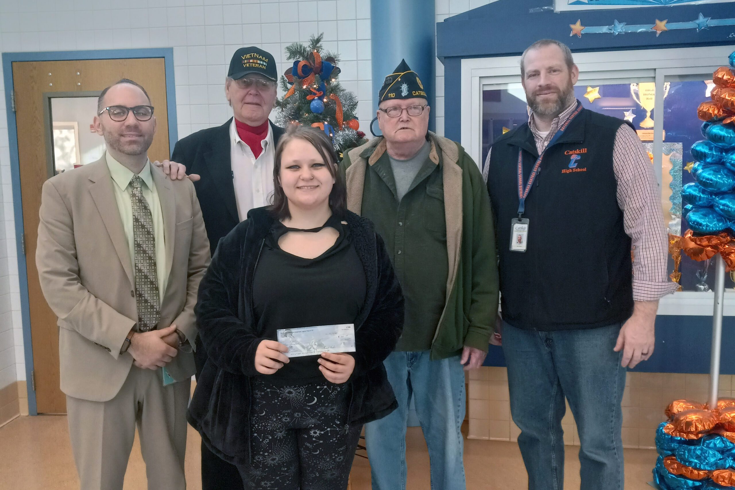 girl posing with check and principal, American legion members, and superintendent