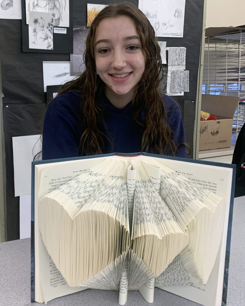Girl posing with book with pages cut out to make hearts