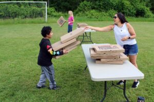 woman helping boy stack up pizza boxes