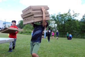 boy carrying stack of pizza boxes