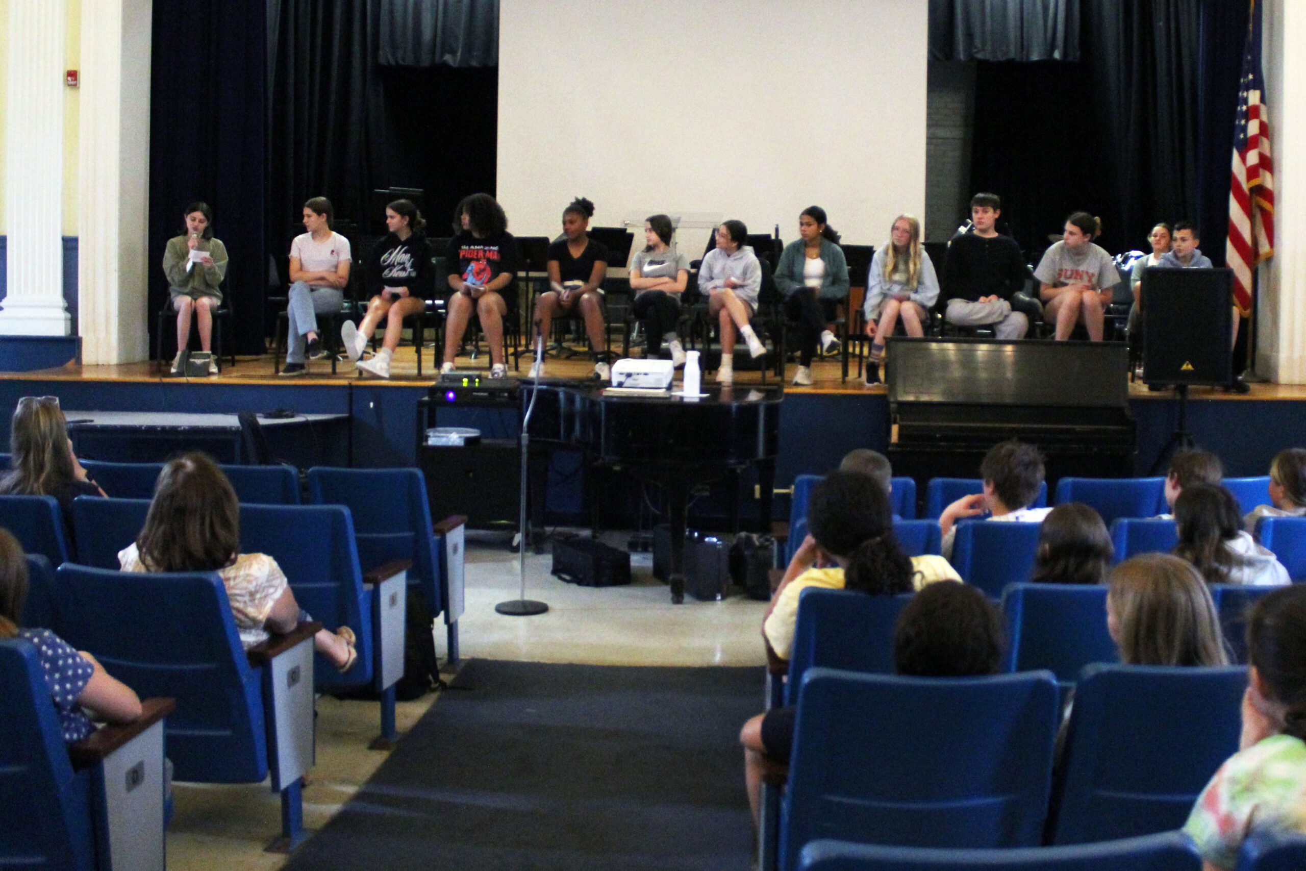 panel of middle schoolers talks in front of audience of fifth graders in auditorium