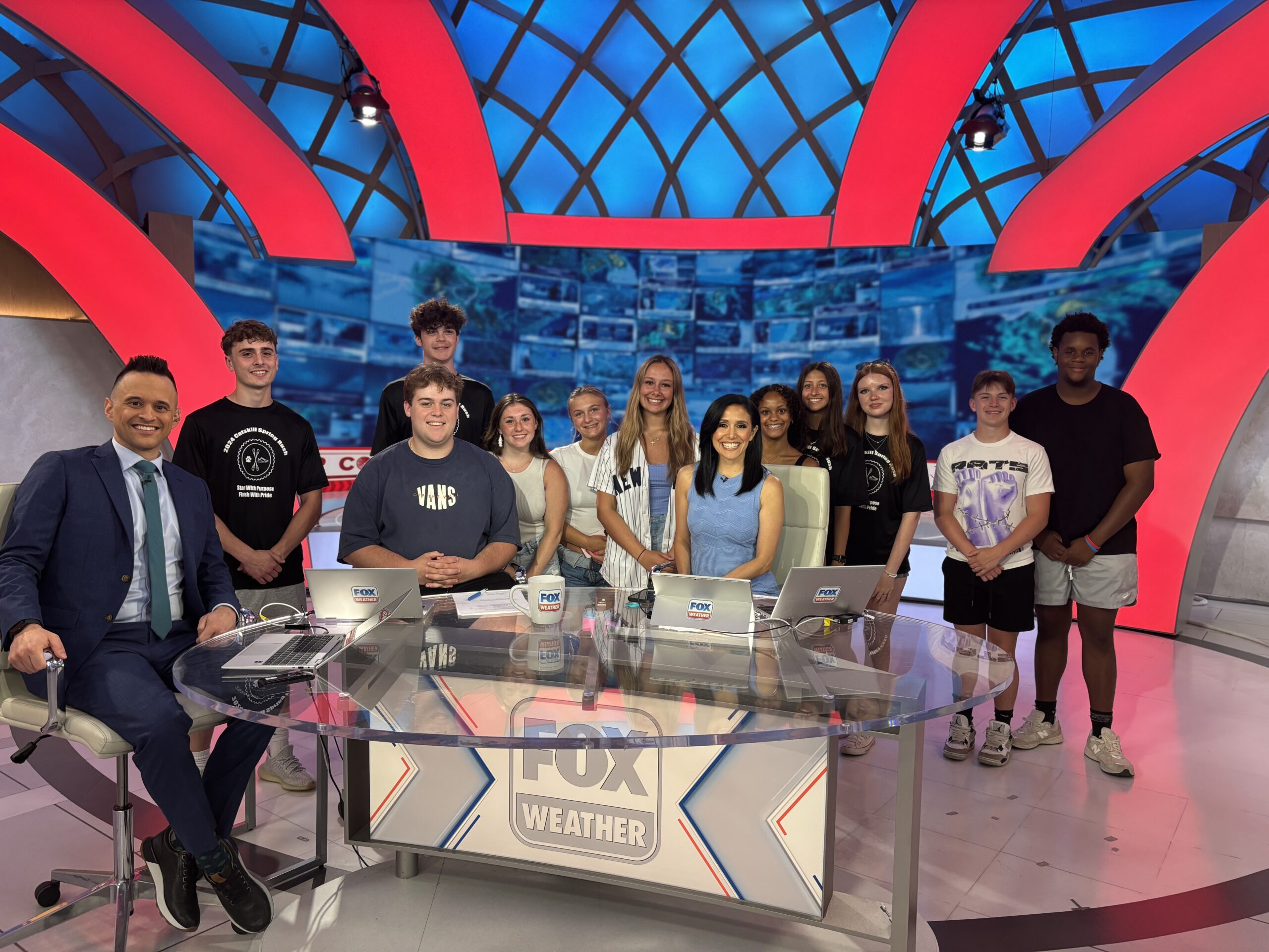 students pose for photo with on-air talent in Fox Weather studio.