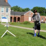 boy priming water rocket with bicycle pump outside CMS while man looks on