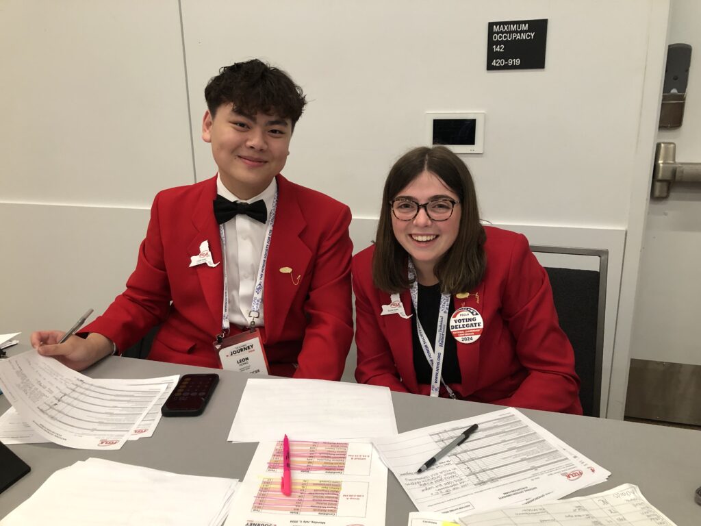 Two students in FCCLA uniforms sitting at table.