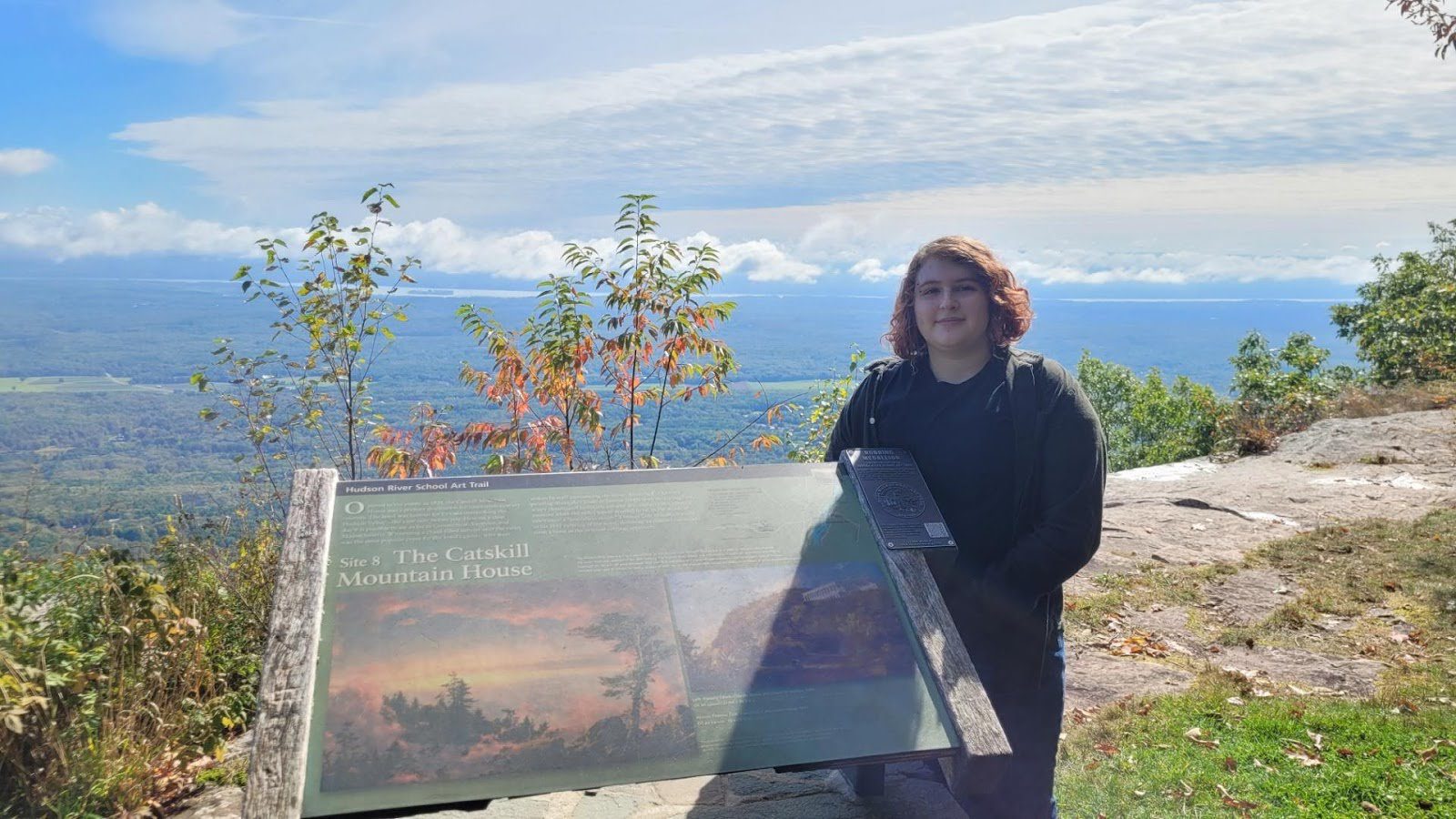 student standing next to trail sign
