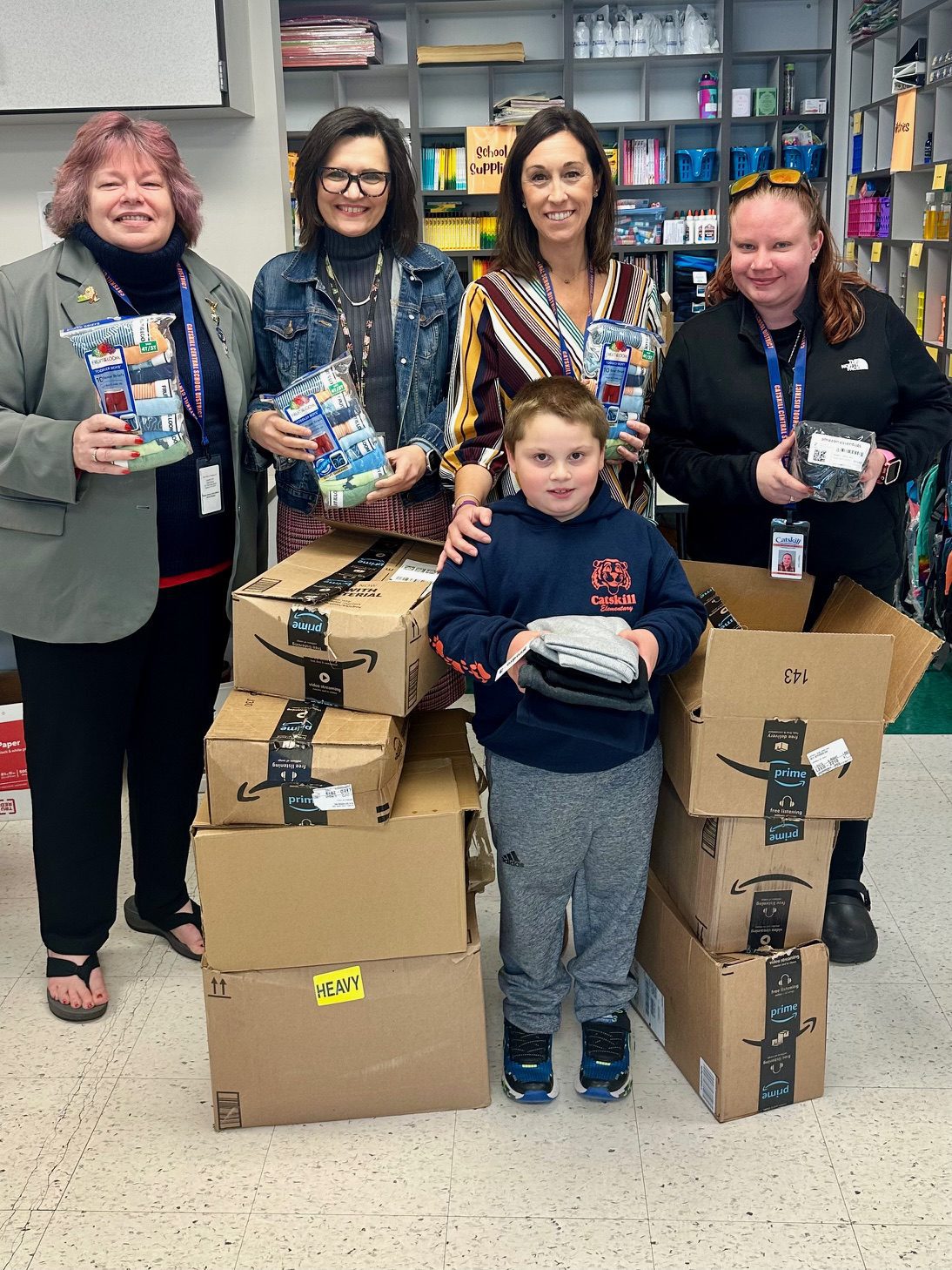 four women and young boy posing with boxes of supplies