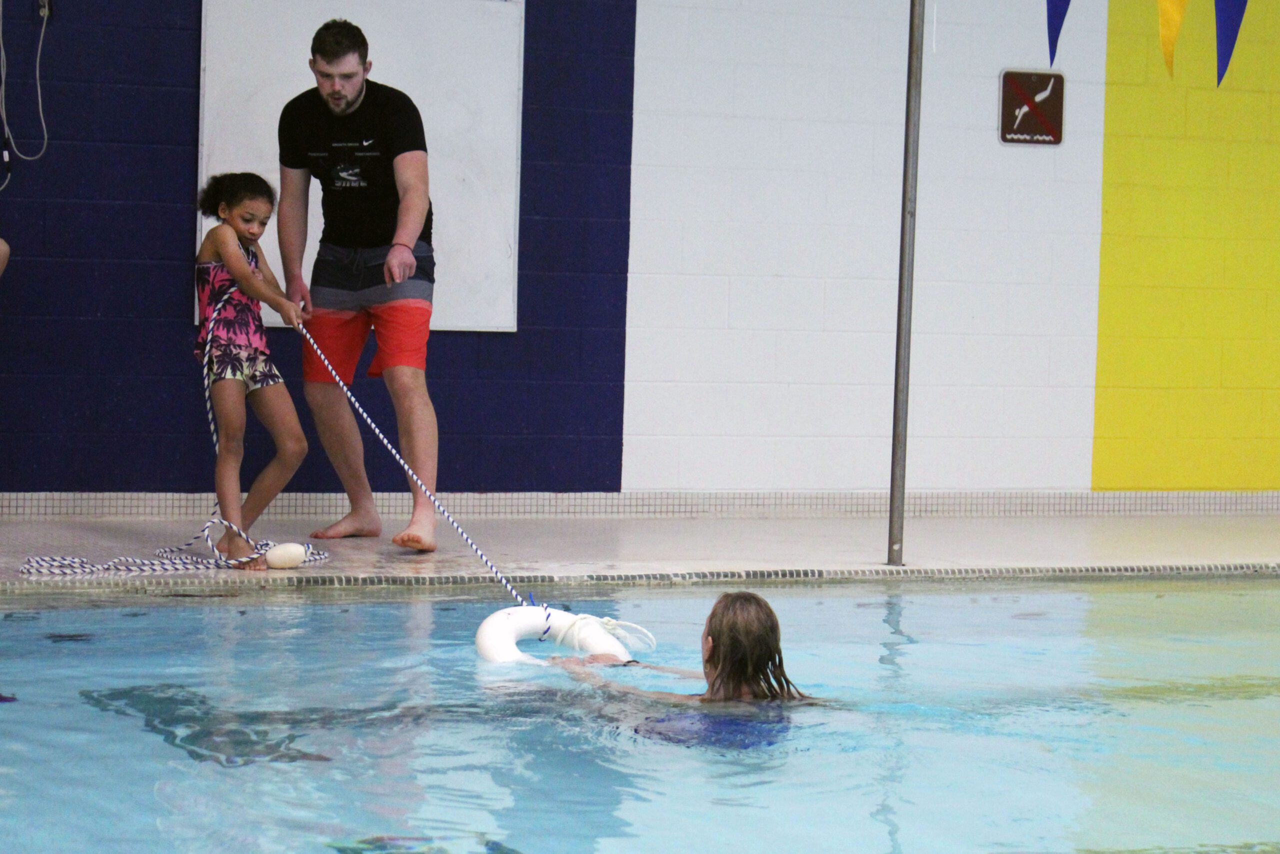 girl tosssing ring to woman in pool