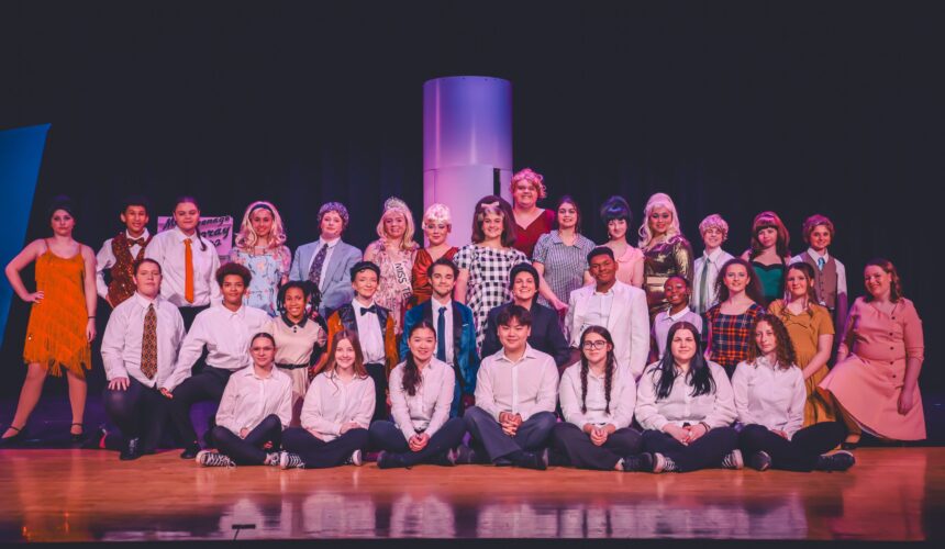 CHS cast of Hairspray pose for group photo on stage