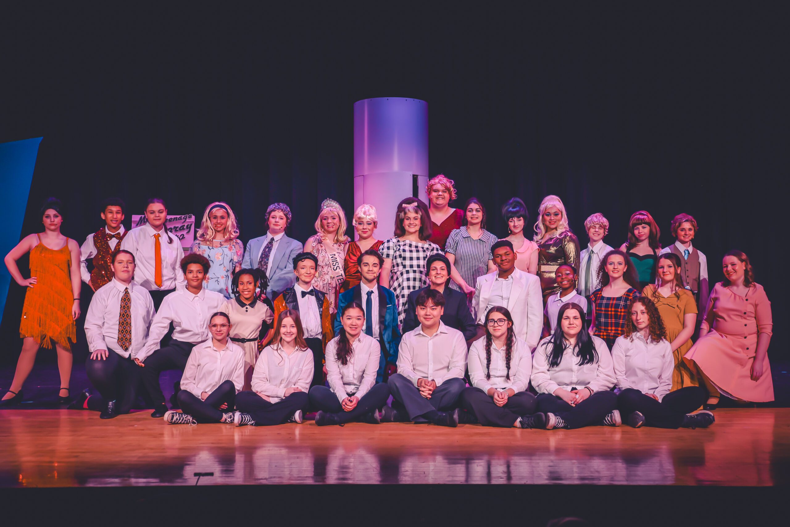 CHS cast of Hairspray pose for group photo on stage