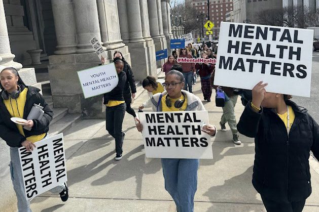 students marching carrying mental health matters signs
