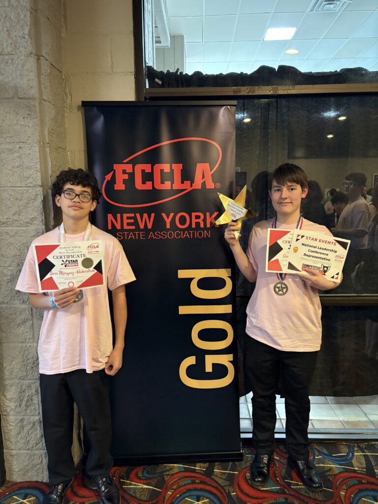 two students posing with gold award sign