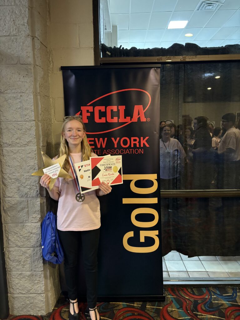 student posing with gold award sign