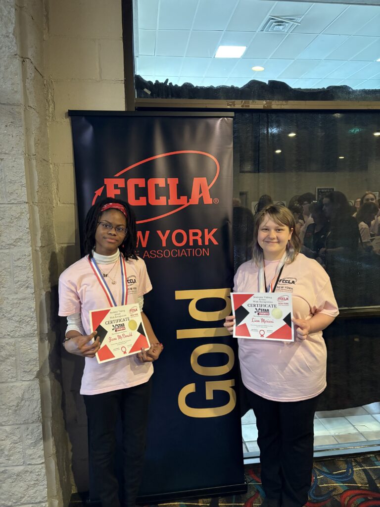 two students posing with gold award sign