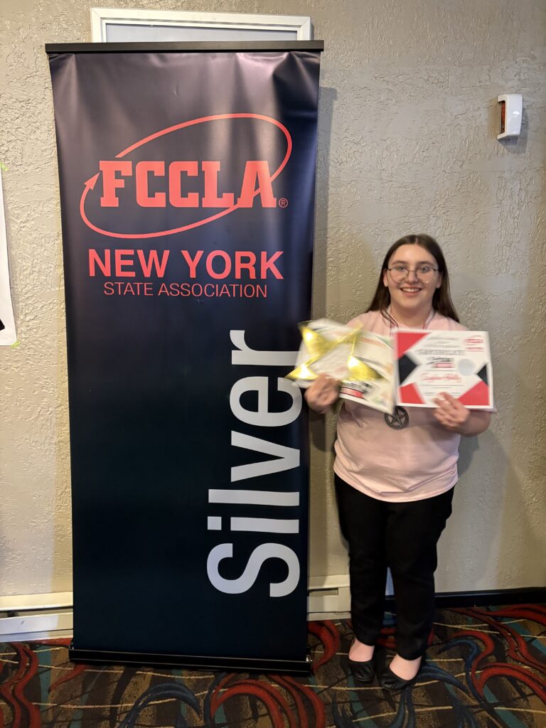 student posing with silver award sign