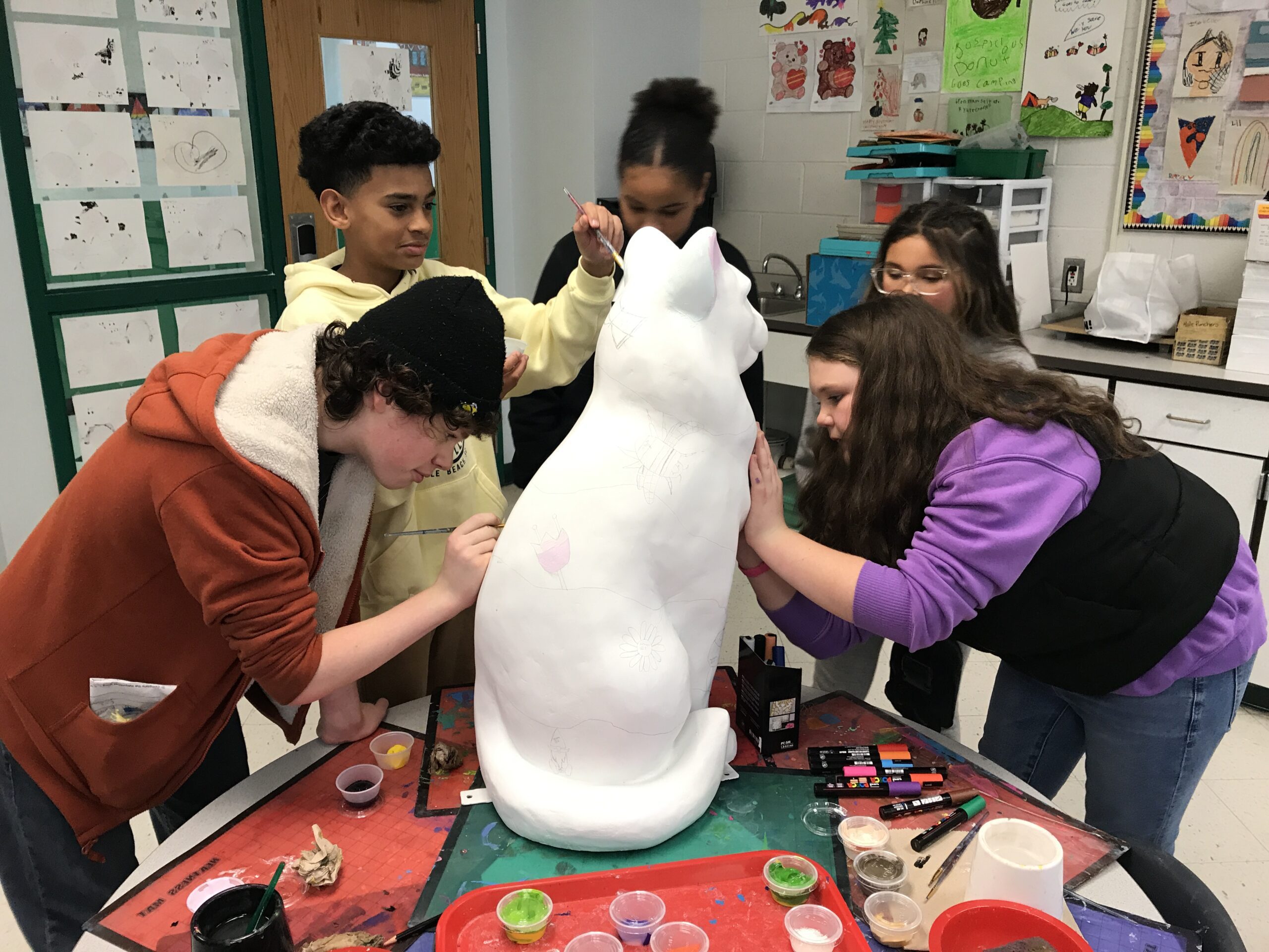 students painting cat statue