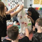 students painting cat statue