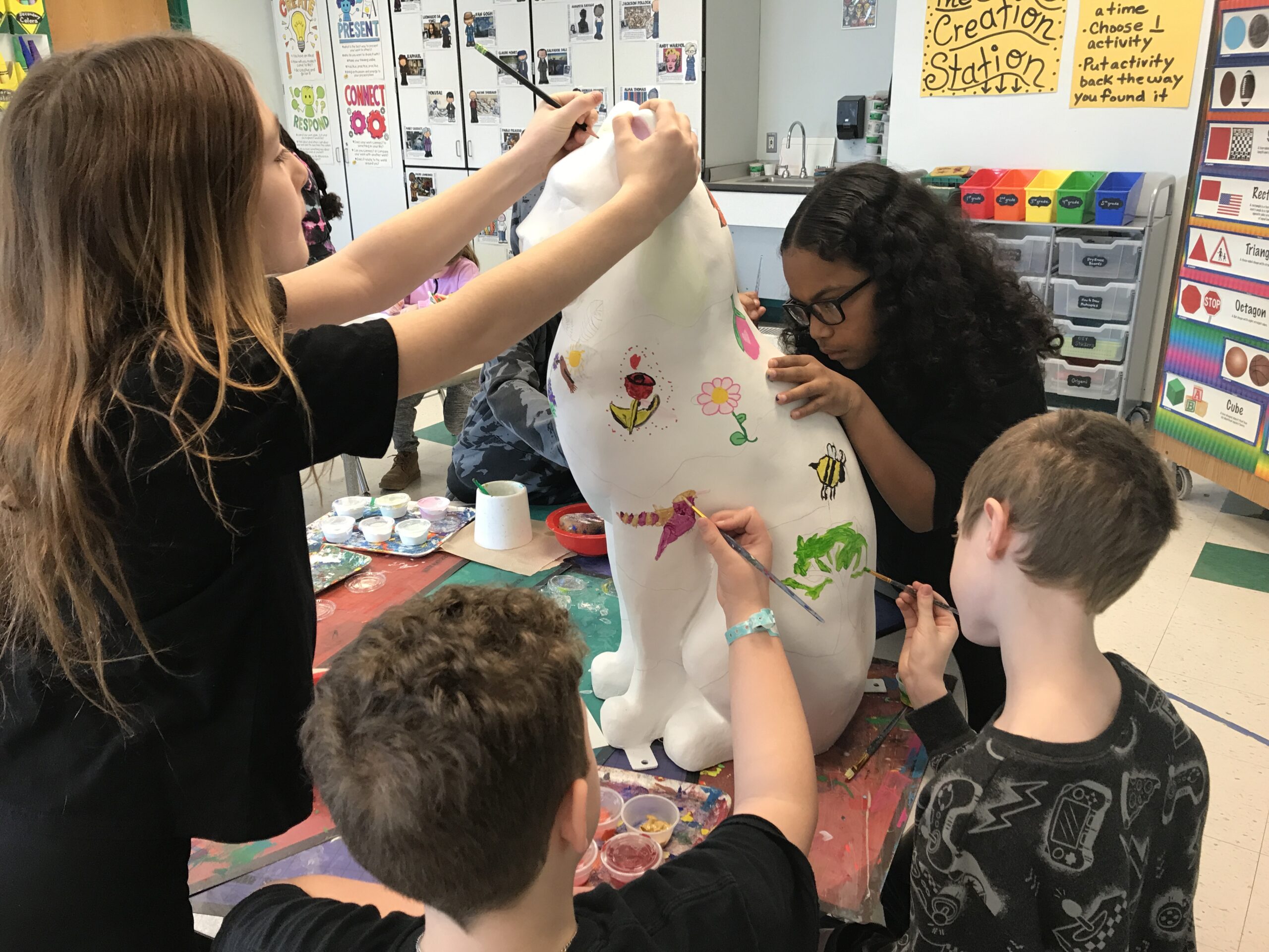 students painting cat statue