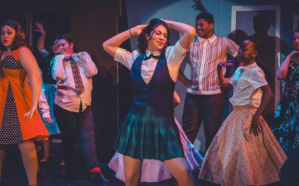 students dancing on stage wear 60s style clothing