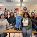 group of high school age students pose with painted cat sculpture