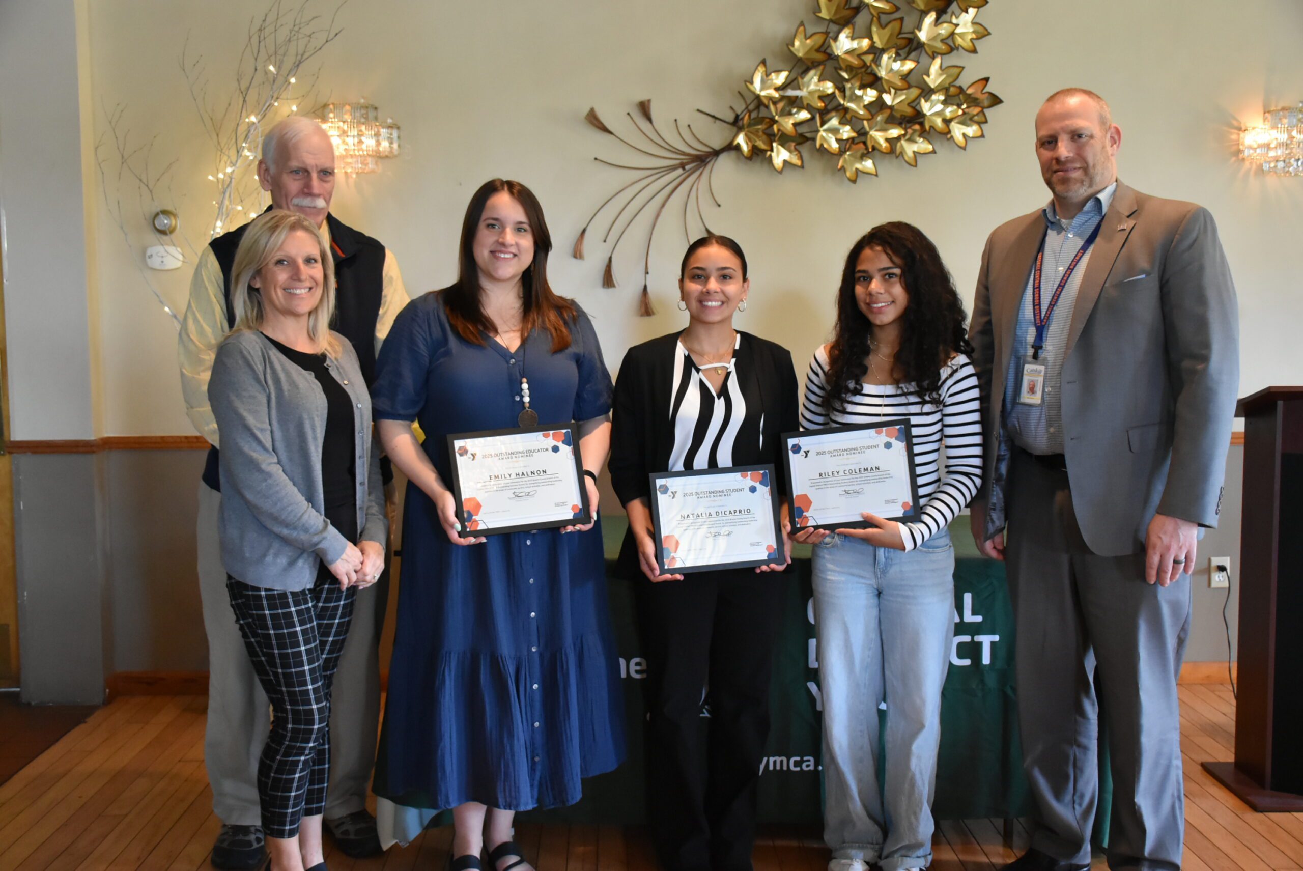 woman and two teenage girls holding certificates flanked by woman and two men