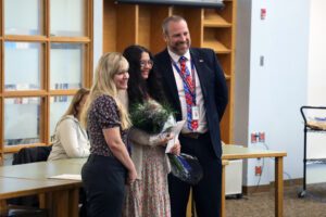 teacher with flowers poses with principal and superintendent
