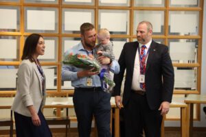 teacher with flowers and baby poses with principal and superintendent