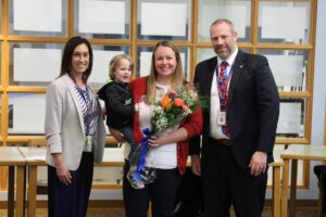 teacher with flowers and young child poses with principal and superintendent