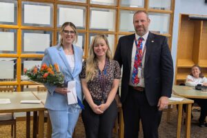 teacher with flowers poses with principal and superintendent
