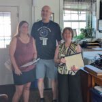 two women and man standing with paper folders