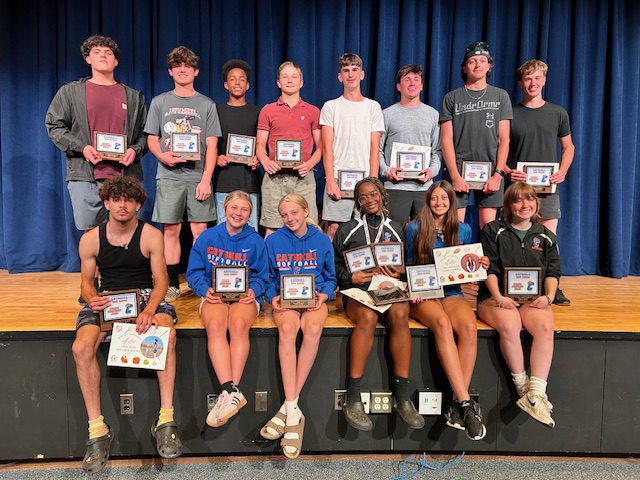 spring sports awardees pose for group photo holding certificates
