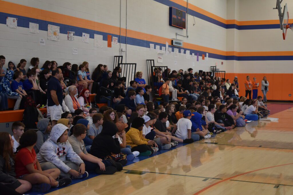 students sitting on bleachers in gym