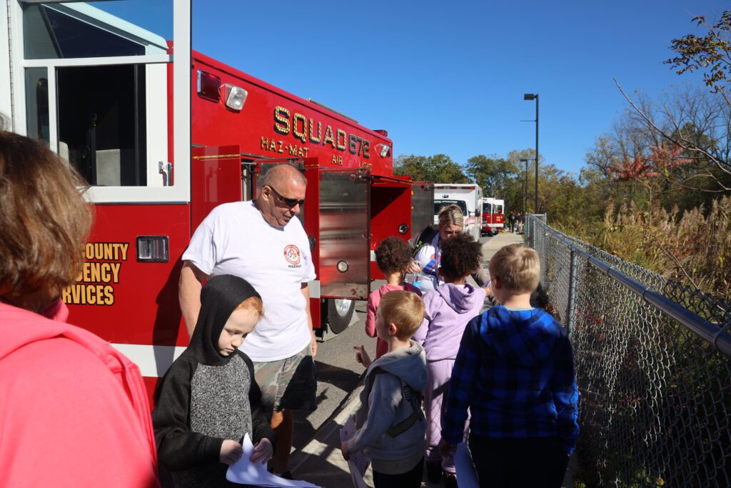 fireman talking to students beside firetruck