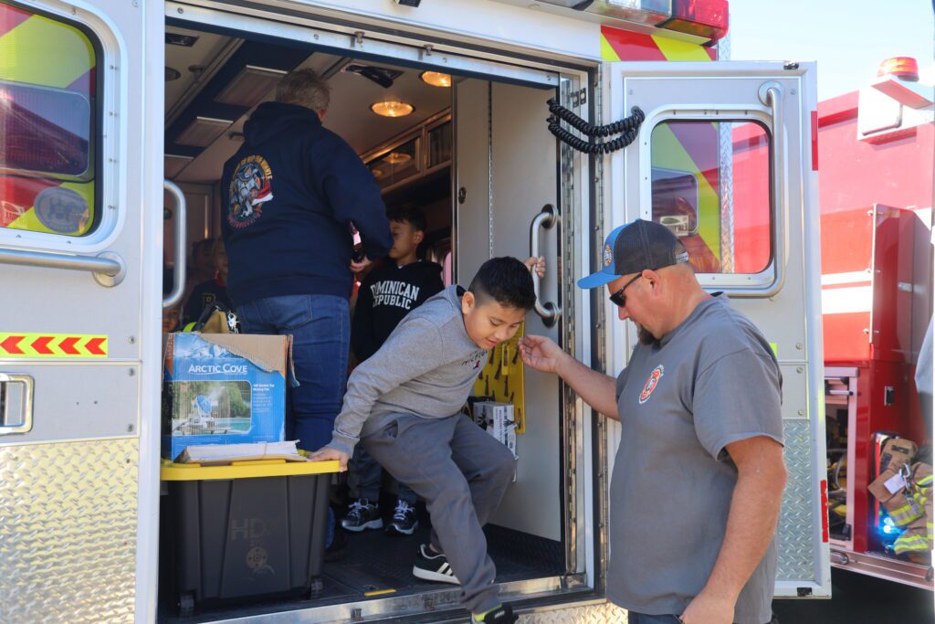boy stepping out of firetruck with help from fireman