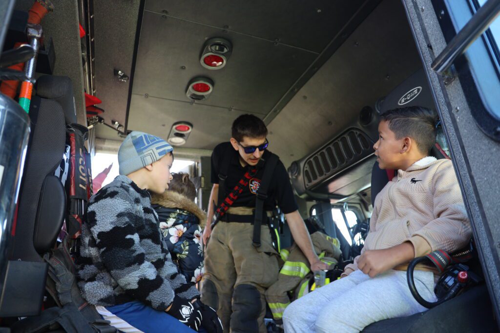 firefighter shows boys inside of fire truck