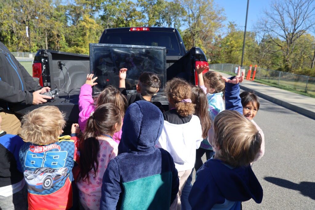 students looking at screen in back of truck