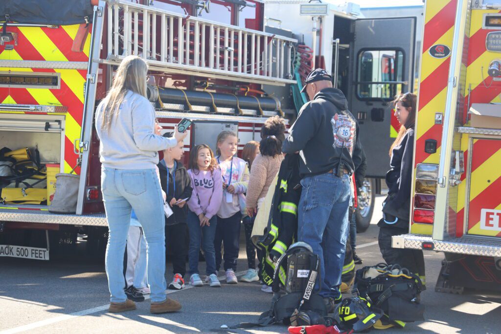 students listening to fireman standing by firetruck